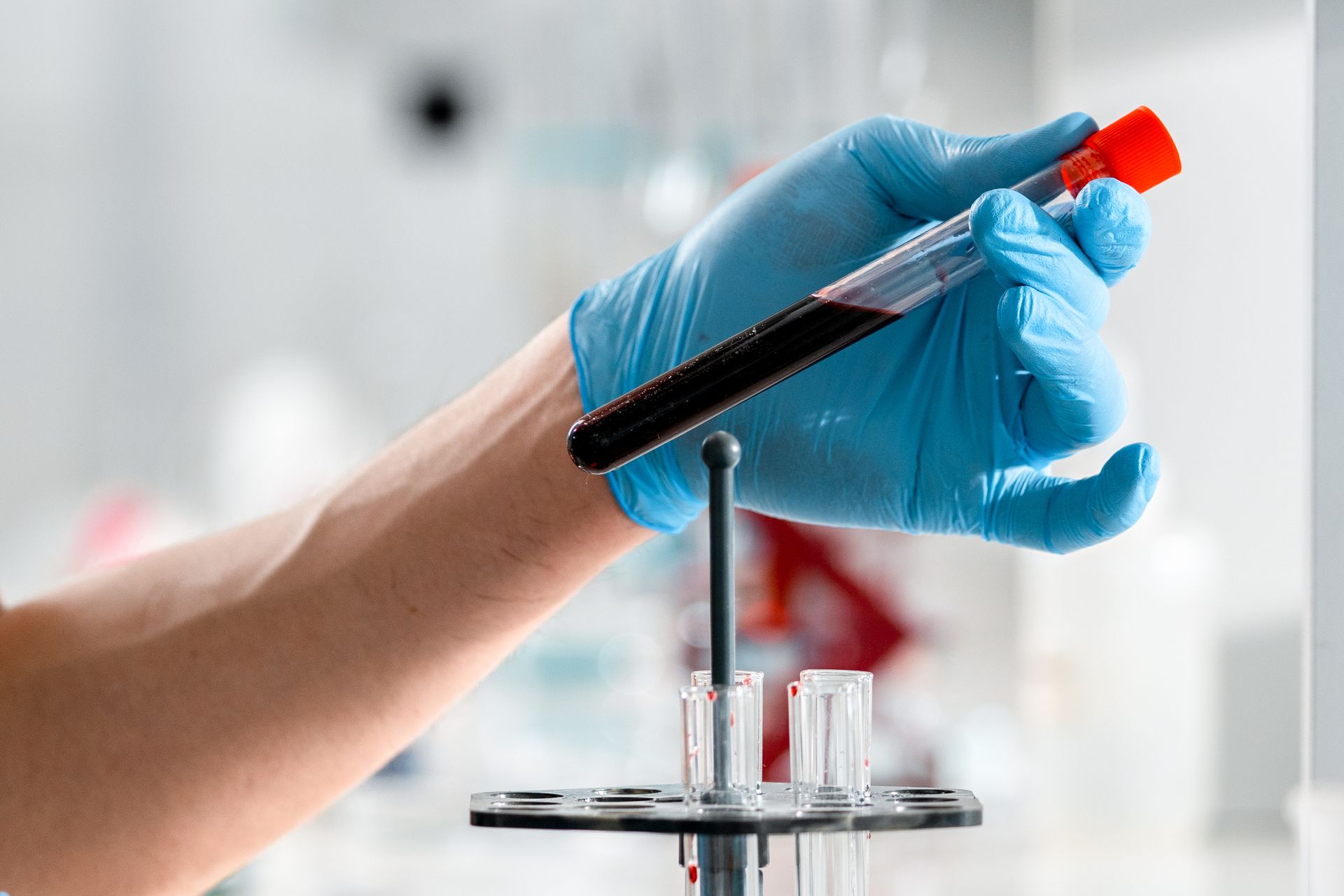 Gloved hand holding a blood sample tube in a lab